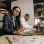 Een ondernemer die de verborgen kosten van zakelijke rekeningen analyseert met een laptop en notitieboek.